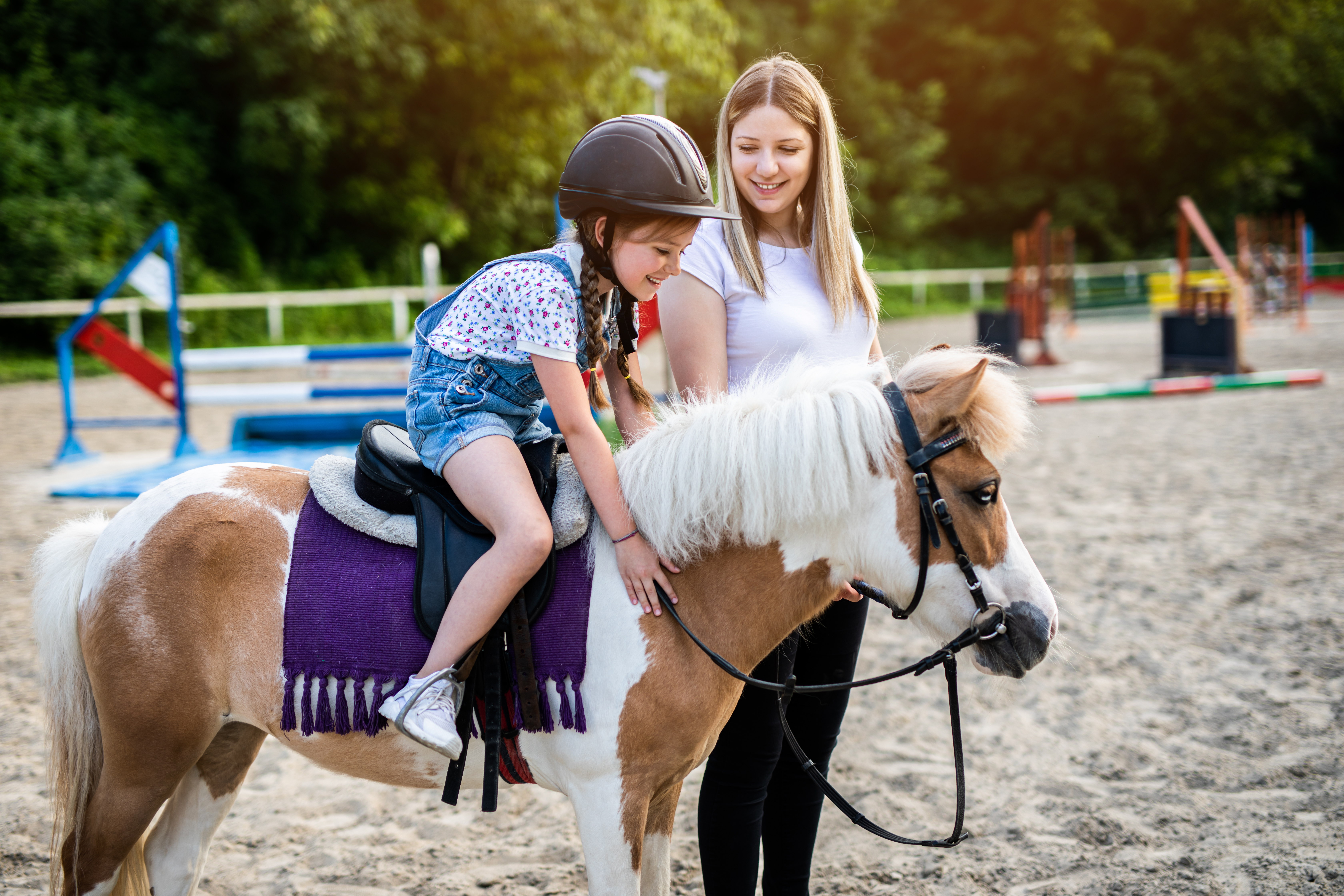 jolie-petite-fille-sa-soeur-ainee-s-amusant-cheval-poney-exterieur-au-ranch